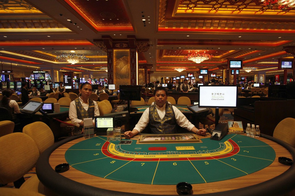 Croupiers sit in front of gaming tables inside a casino on the opening day of Sands Cotai Central, Sands’ newest integrated resort in Macau