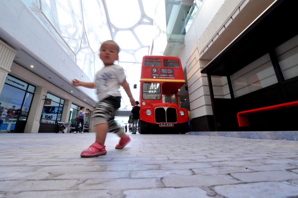 Un bimbo corre davanti a un double-decker bus londinese