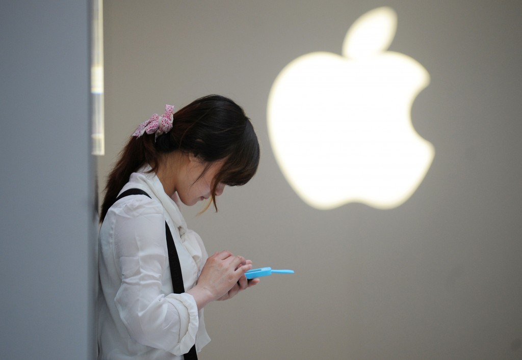 Una ragazza cinese concentrata sul suo Iphone fuori da un Apple store a Shanghai