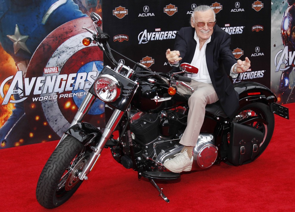 Stan Lee in sella ad una motocicletta mima il gesto dell’Uomo Ragno alla prima di “The avengers”